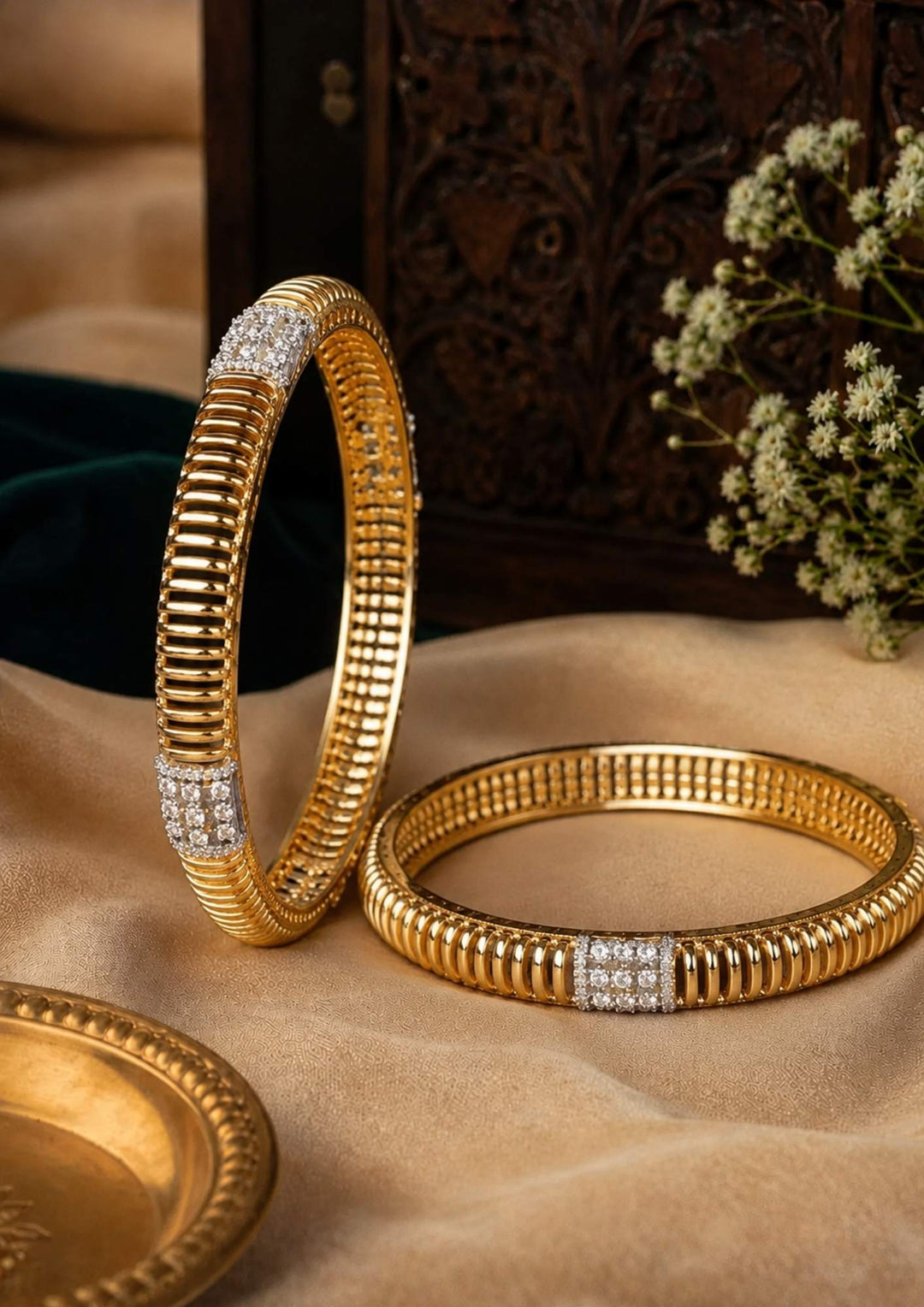 Gold bangles with diamond accents on a textured surface with a decorative background.