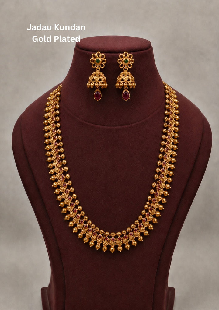 Traditional style gold plated temple long haram necklace designed with structured Nakshi panels  green bead accents, and an elegant matte gold finish that gives a graceful traditional look for festive celebrations, poojas, family functions, and bridal outfits.