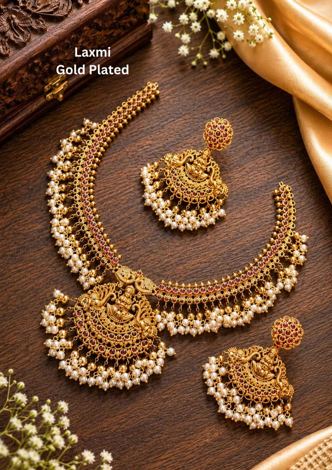 Gold plated short temple necklace and matching hanging earrings set featuring a central design of Goddess Lakshmi Devi seated on a lotus, surrounded by sparkly white Kundan stone settings. The entire lower border of the necklace and earrings is decorated with dense, fringe clusters of small white pearls, providing a classic heritage look suitable for weddings and family functions.