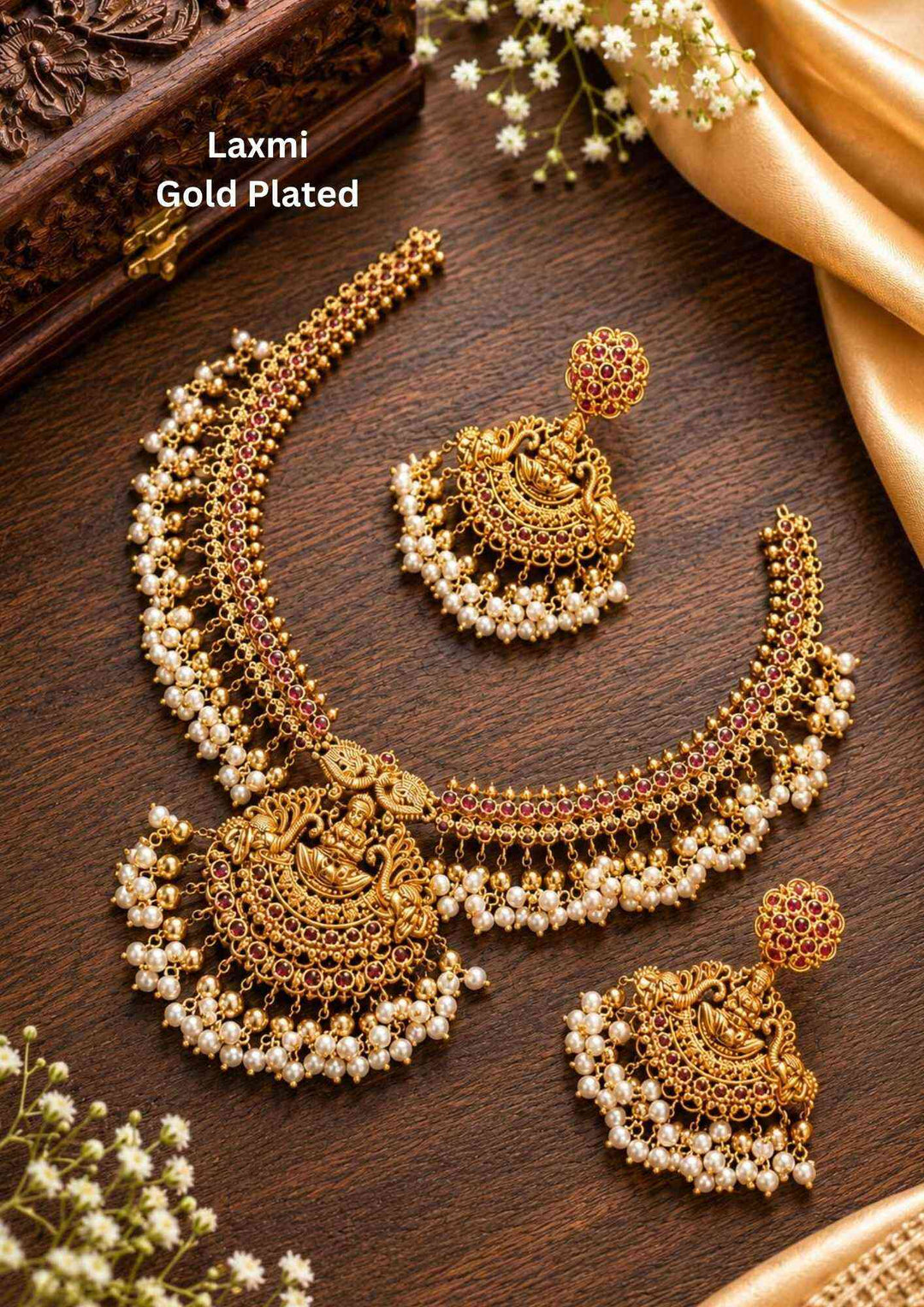 Gold plated short temple necklace and matching hanging earrings set featuring a central design of Goddess Lakshmi Devi seated on a lotus, surrounded by sparkly white Kundan stone settings. The entire lower border of the necklace and earrings is decorated with dense, fringe clusters of small white pearls, providing a classic heritage look suitable for weddings and family functions.