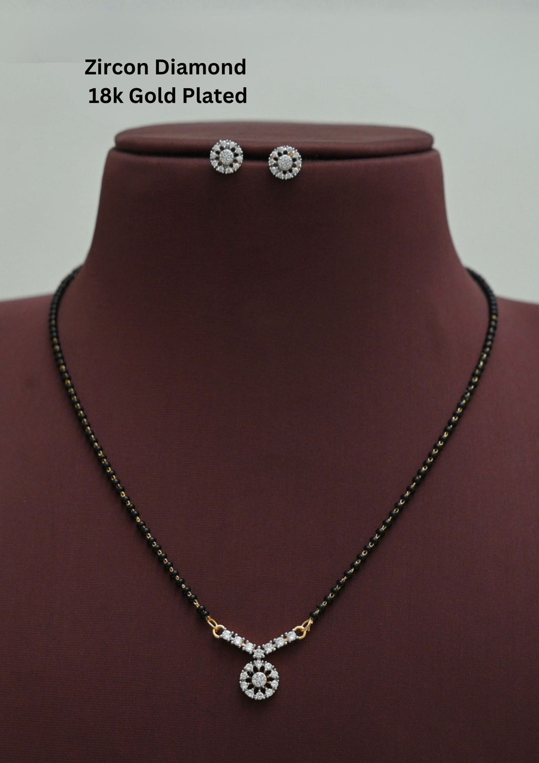 Modern Zircon Diamond gold plated mangalsutra necklace The design features a delicate gold long chain transitioning into sections of traditional small black beads on both sides. The central pendant showcases a sleek, contemporary curved V shape with wheel pendant with sparkling white cubic zirconia stones. It come with matching earrings in wheel shaped studs This elegant neckpiece perfect for daily wear, office wear, and casual outfits.