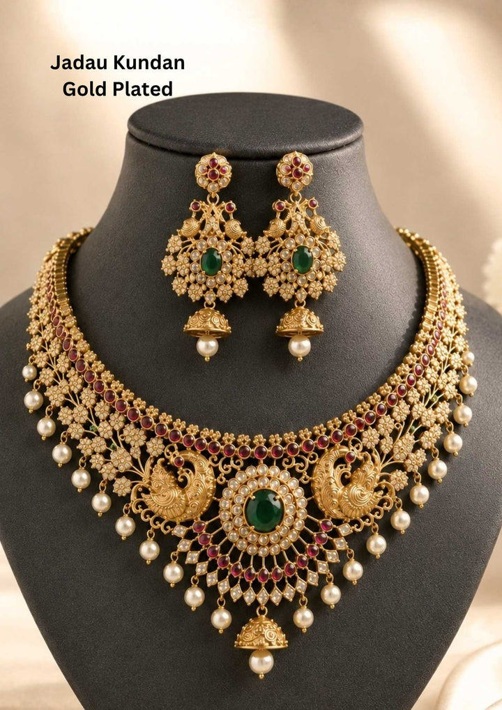 Gold pleted jadau kundan chocker set designed with twin peackocks and in center big emerald stone and bottom comes with bell and pearls to entire chocker and this set comes with matching big earrings perfect for birdal wear, functions