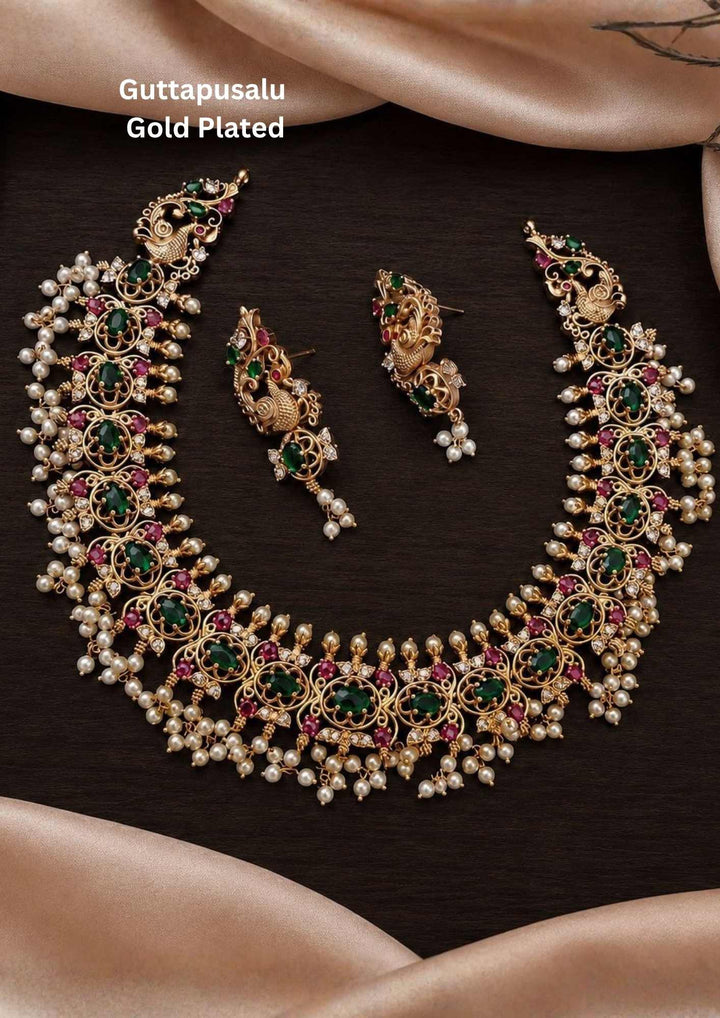Gold-plated necklace and earrings south indian Woman wearing a traditional necklace and earrings Gold-plated necklace and earrings set with pearls and gemstones comes with jadau kundan and it comes with in detailed peacock design and  comes with pearl beads and looks traditional for weeding , functional 