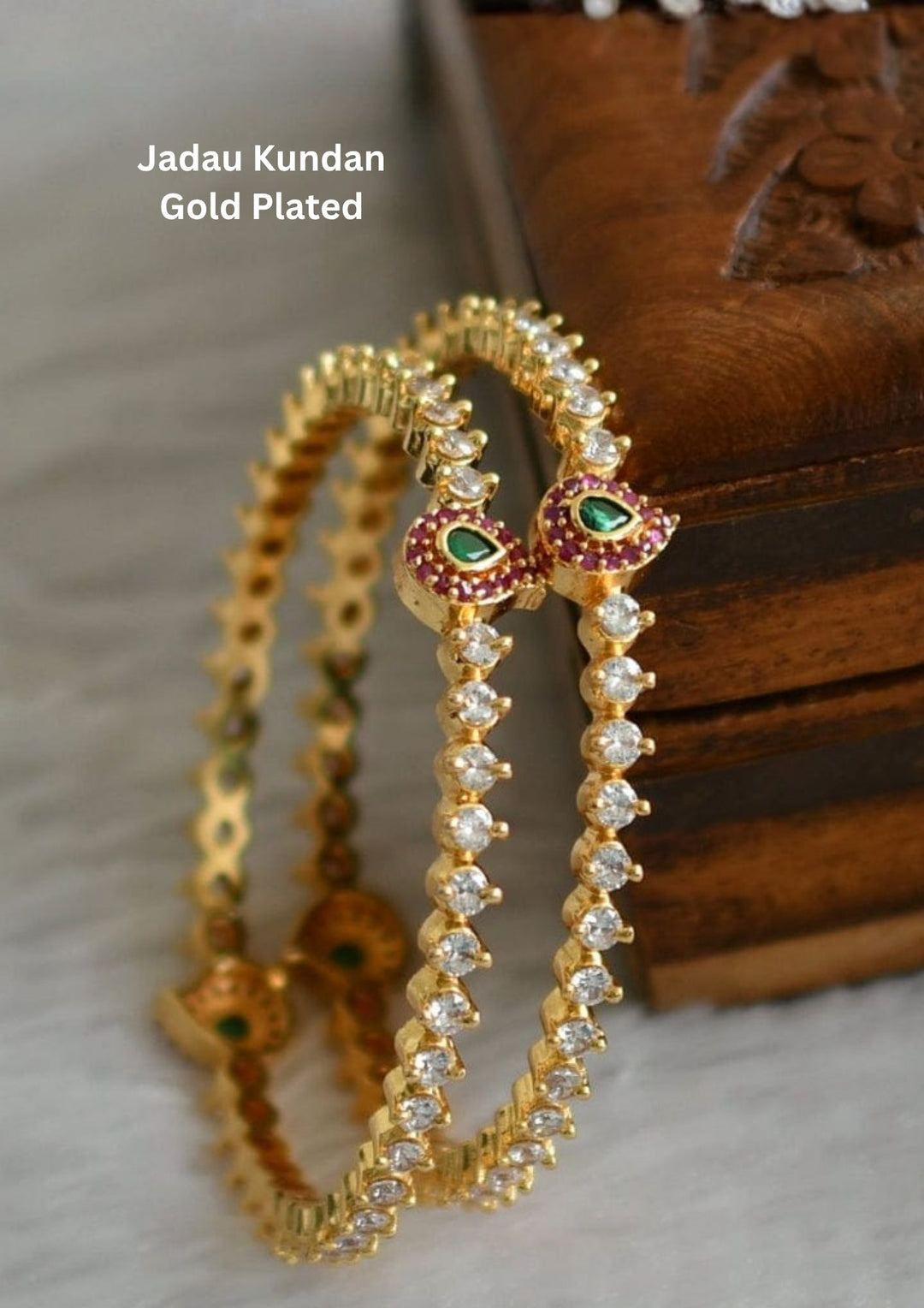 Elegant Jadau Kundan gold plated bangles featuring sparkling kundan stones with emerald teardrop accents. Perfect for weddings and festive occasions.