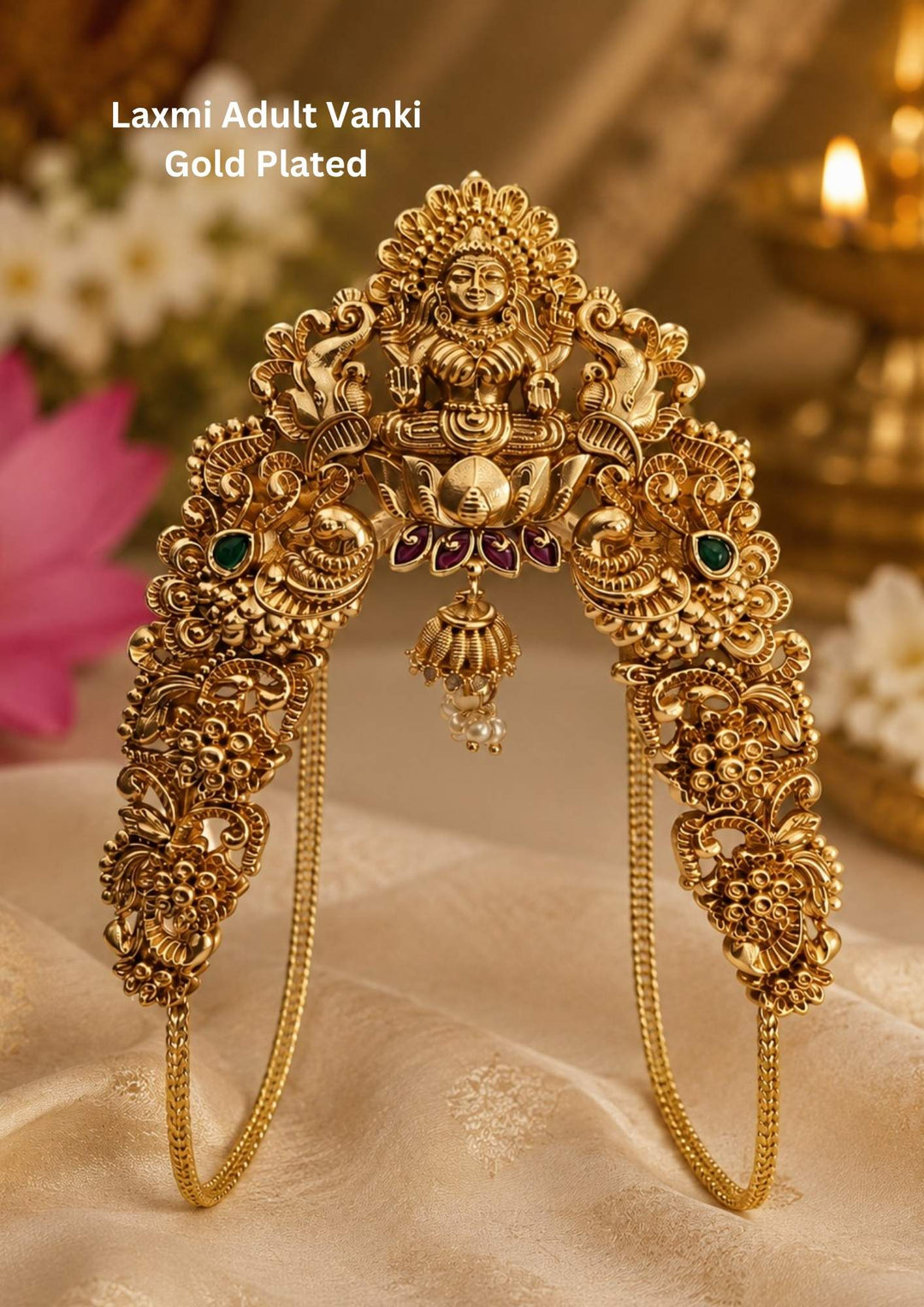 Traditional Lakshmi temple design gold plated vanki featuring an intricately carved Goddess Lakshmi seated on a lotus motif. The armlet showcases detailed peacock and floral patterns with green stone accents, ruby-colored highlights, and elegant pearl danglers, creating a rich South Indian bridal look. Perfect for weddings and festive occasions.