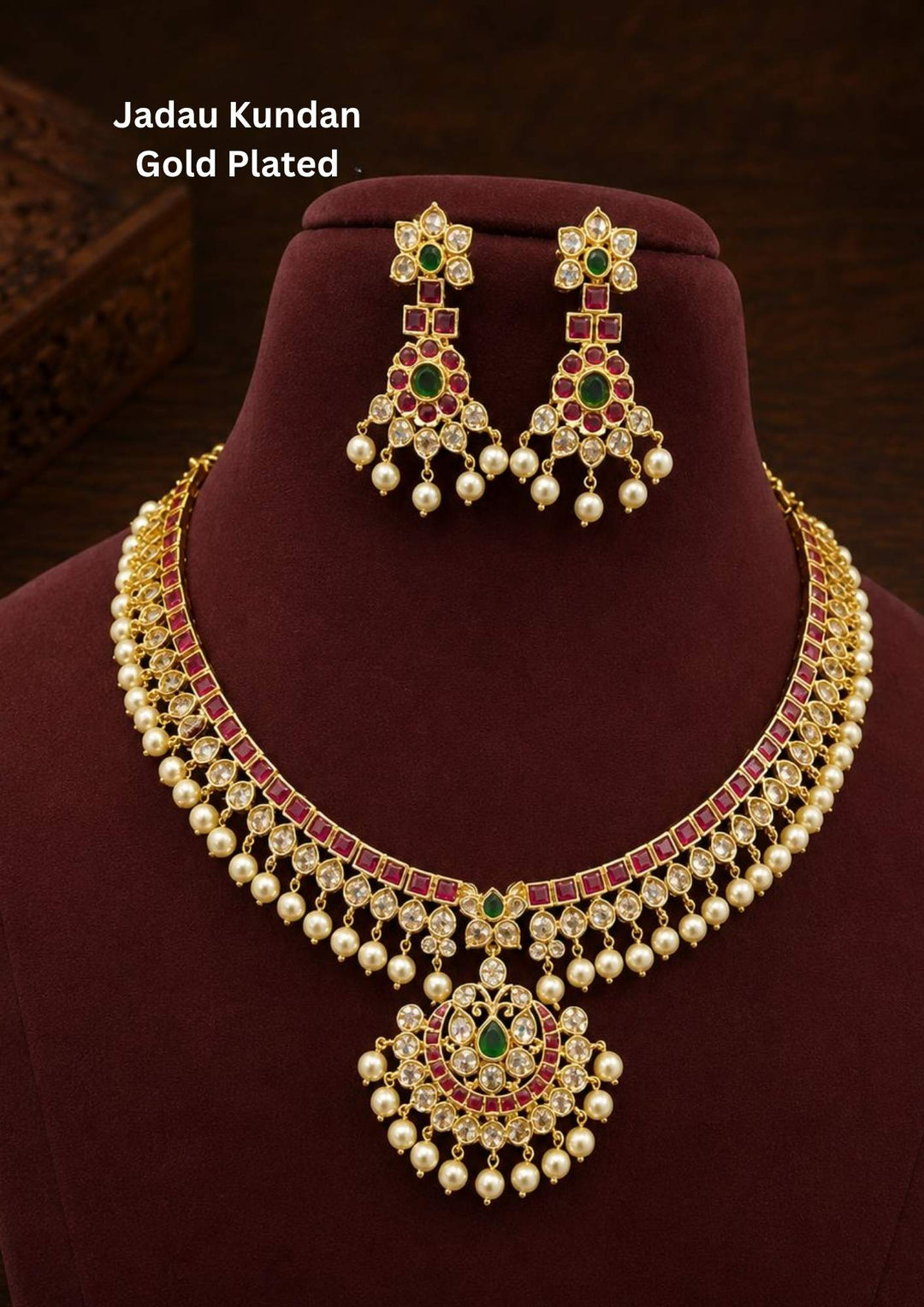 Gold plated choker necklace and matching hanging earrings set featuring a band lined with square red stones and small white crystals. A round crescent pendant hangs at the center, decorated with white stones, a green stone center, and a simple row of hanging white pearls along the bottom edge, providing a classic look suitable for festivals and family functions.