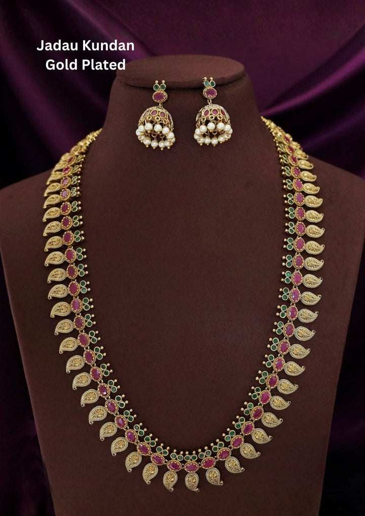 Traditional jadau kundan gold plated necklace set featuring intricate floral motifs adorned with vibrant pink and green stones along with elegant pearl drops. The matching statement earrings enhance the ethnic charm, creating a luxurious and festive jewelry design perfect for weddings and traditional celebrations.
