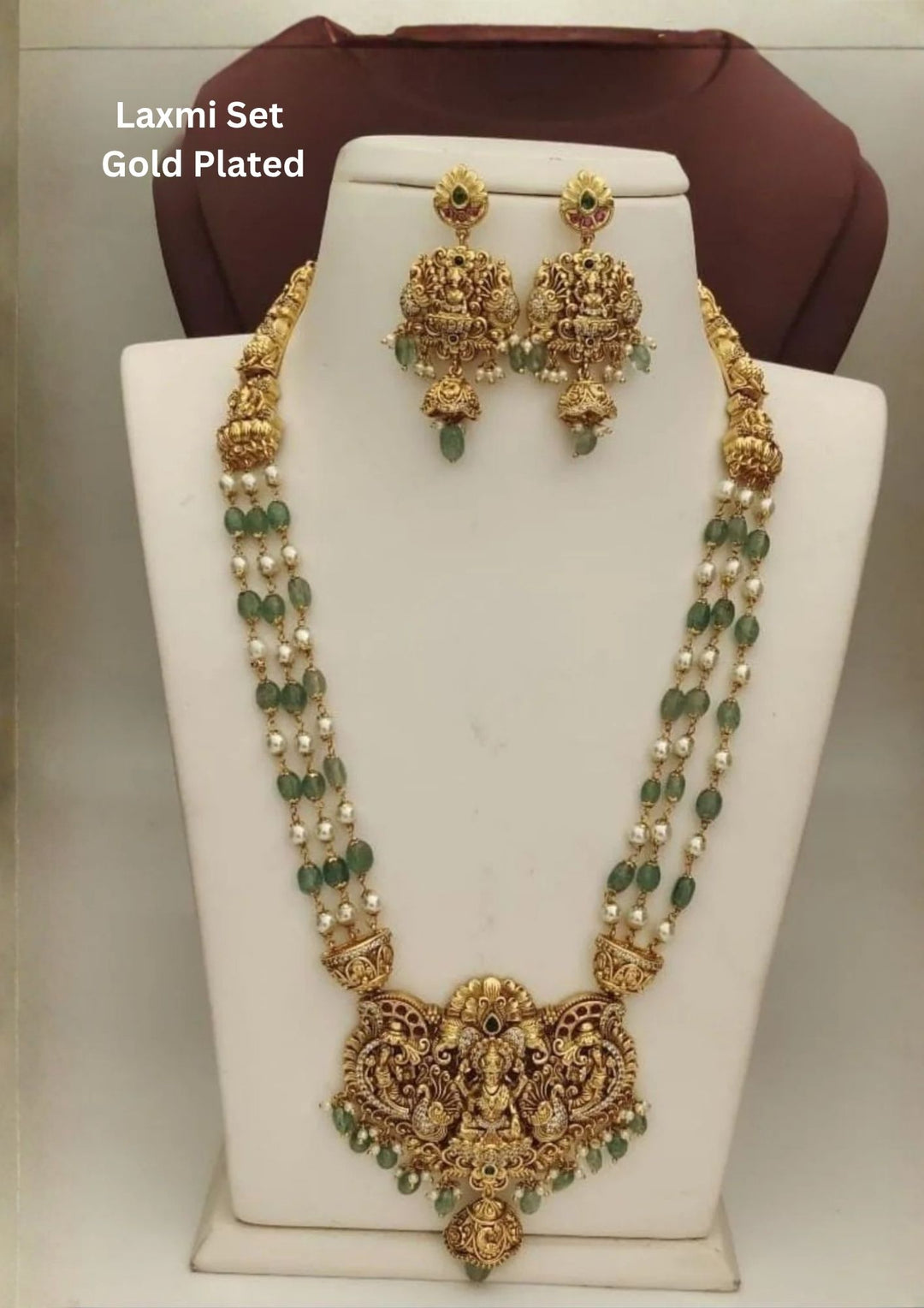 Jadau Kundan Gold Plated Lakshmi Temple Beaded Necklace With Earrings designed with pastel green beads and white pearls with gold Goddess Laxmi Goddess Lakshmi pendant design, border with bnoth green and white pearls and beads, temple jewellery style, lightweight comfort, sweat resistant coating, anti-fade polish, and skin-friendly wear suitable for weddings, festivals, poojas and bridal wear