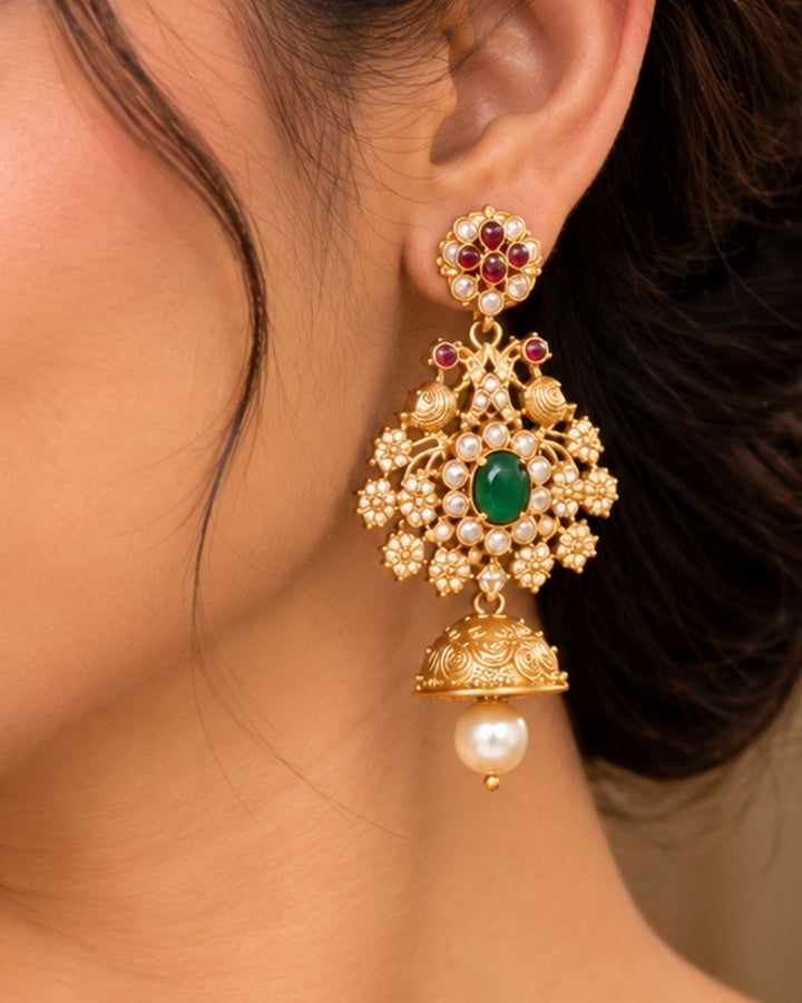 Gold pleted jadau kundan chocker set designed with twin peackocks and in center big emerald stone and bottom comes with bell and pearls to entire chocker and this set comes with matching big earrings perfect for birdal wear, functions
