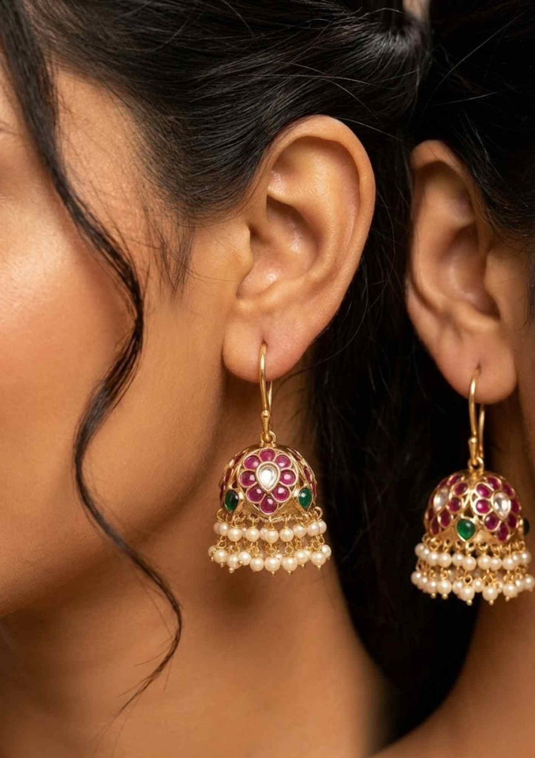 Close-up of a South Indian woman wearing gold earrings with red and green gemstones in south indain traditional women can be used for weddings , dailywear, functions and can gift 
