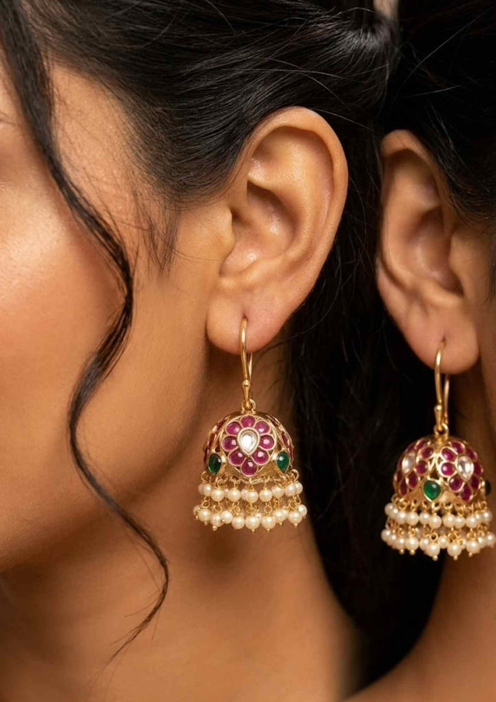 Close-up of a South Indian woman wearing gold earrings with red and green gemstones in south indain traditional women can be used for weddings , dailywear, functions and can gift 