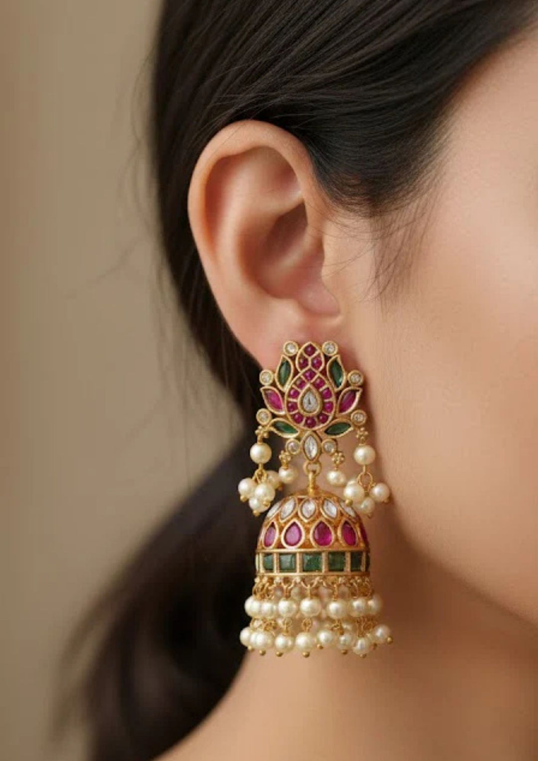 Close-up view of a woman wearing heavy Jadau Kundan Jhumka Earrings with large lotus flower-shaped stud design, dome-style buttalu jhumka pattern, colorful kempu stones, and  with traditional guttapusalu detailing. The earrings give a grand bridal and festive jewelry look with lightweight comfort, sweat proof quality, anti-fade colour, skin-friendly finish, and are suitable for weddings, receptions, festivals, and party wear.