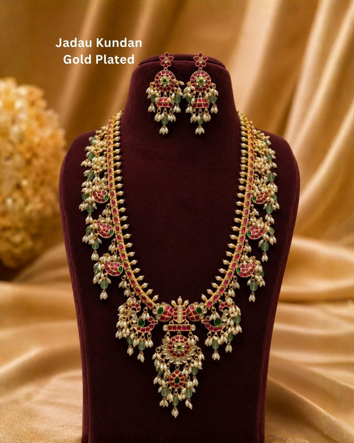 Gold necklace Set with a detailed pendant and earrings  on a white background with green and red stones come with jadau kundan in necklace set with beads and in pendent shows clear design and in detailed shown in picture it will not fade color and water proof can used for festivals, bridals, and weeding&