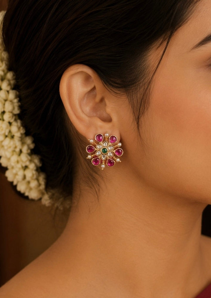Close-up of a woman wearing a floral earring with gemstones.