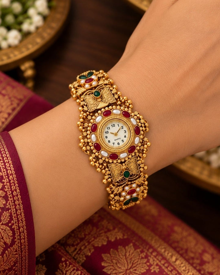 Traditional gold plated bracelet watch displayed diagonally on a beige stone surface with cream fabric and wooden accents.