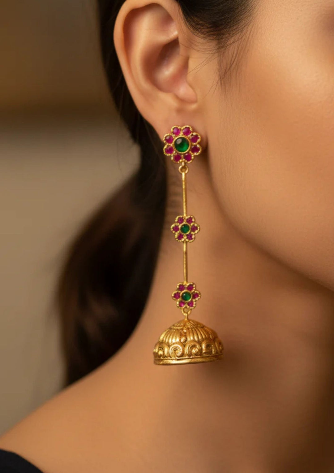 Gold earrings with green and red stones worn by a south indian women looks very detailing and also women shows how it looks to every one very traditional 