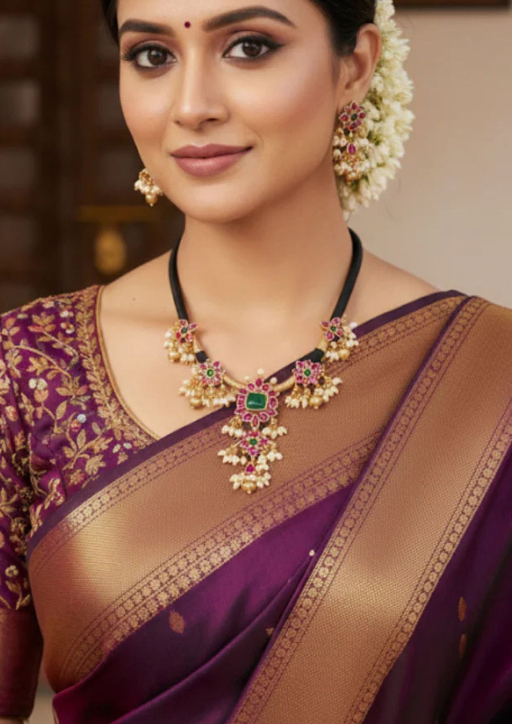 South Indian women wearing matte gold plated guttapusalu necklace and jhumkas with a traditional and simple look. It is designed with red kempu stones and rice shape pearlsPerfect for temple visits, weddings, and functions. The set is lightweight, skin-safe, and gives a rich bridal-style look.