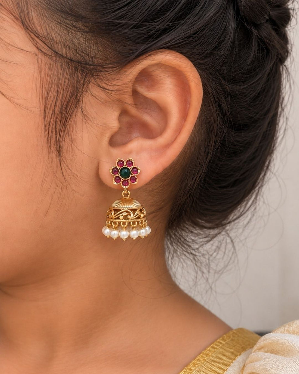Gold-plated jhumka earrings with pearls and gemstones looks very traditional with flower design  