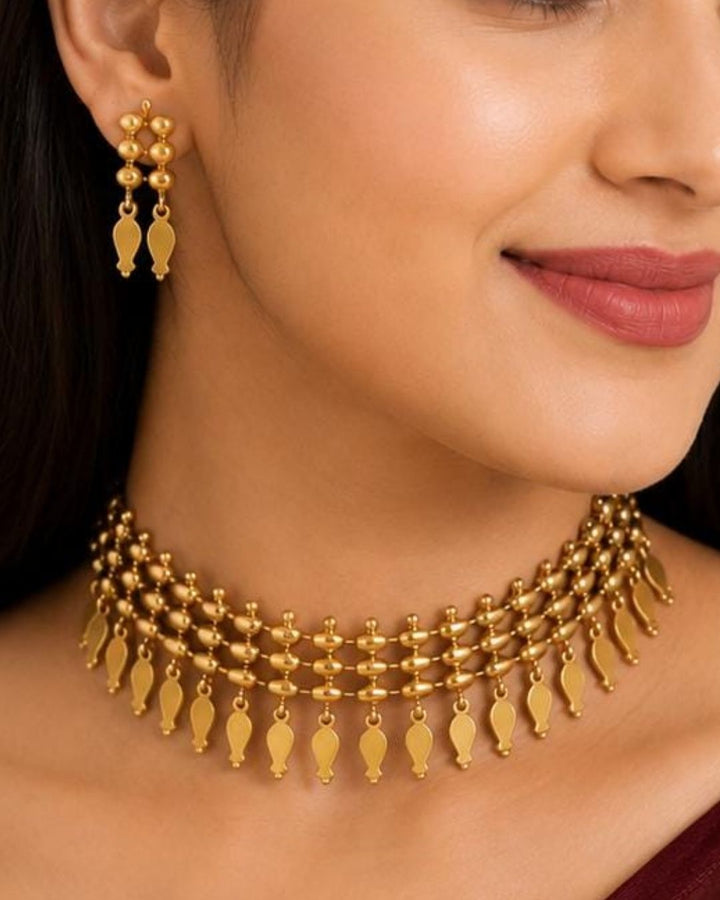 Beautiful gold plated choker necklace and matching earrings featuring multiple rows of textured beads and traditional leaf-shaped dangling elements. Perfect for festive occasions, traditional wear, daily wear, and gifting.