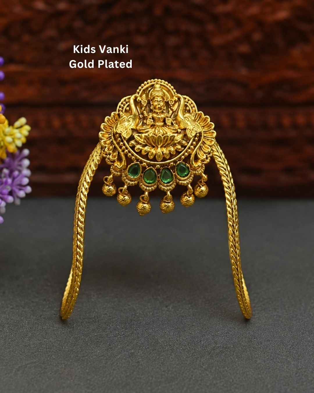 Beautiful gold plated kids vanki featuring an intricately crafted Goddess Lakshmi design with a lotus motif, four green stones, detailed traditional patterns, and elegant dangling gold embellishments. Perfect for traditional wear, weddings, festivals, classical dance, special occasions, and gifting.