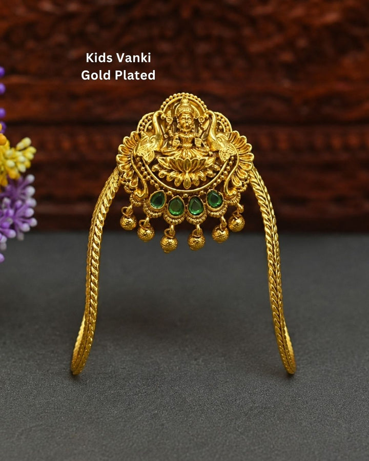 Beautiful gold plated kids vanki featuring an intricately crafted Goddess Lakshmi design with a lotus motif, four green stones, detailed traditional patterns, and elegant dangling gold embellishments. Perfect for traditional wear, weddings, festivals, classical dance, special occasions, and gifting.