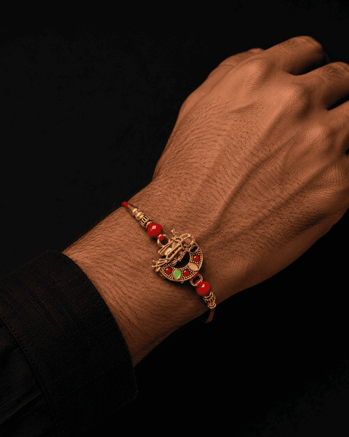 Beautiful gold plated Krishna Rakhi featuring a divine Lord Krishna design with flute, decorative red beads, and premium craftsmanship. Perfect for Raksha Bandhan gifting.