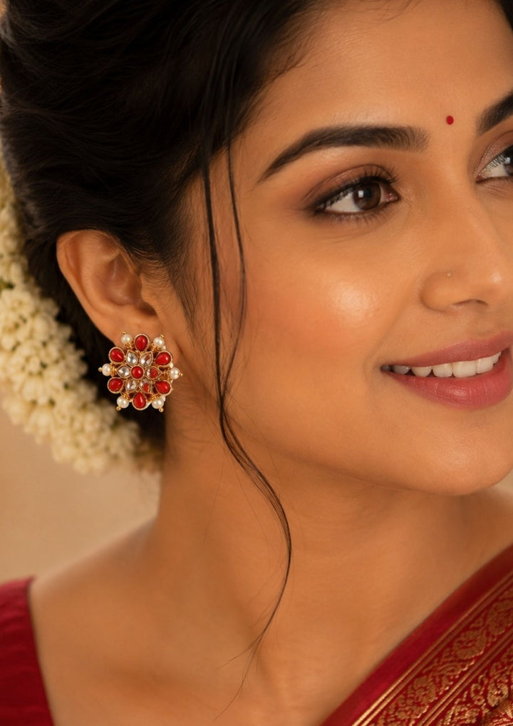 Close up of a south indian women wearing a Premium coral gold plated earrings crafted with intricate floral craftsmanship, radiant red coral stones, brilliant kundan detailing, and pearl embellishments. A timeless jewellery piece that complements silk sarees, lehengas, and festive outfits with effortless elegance.