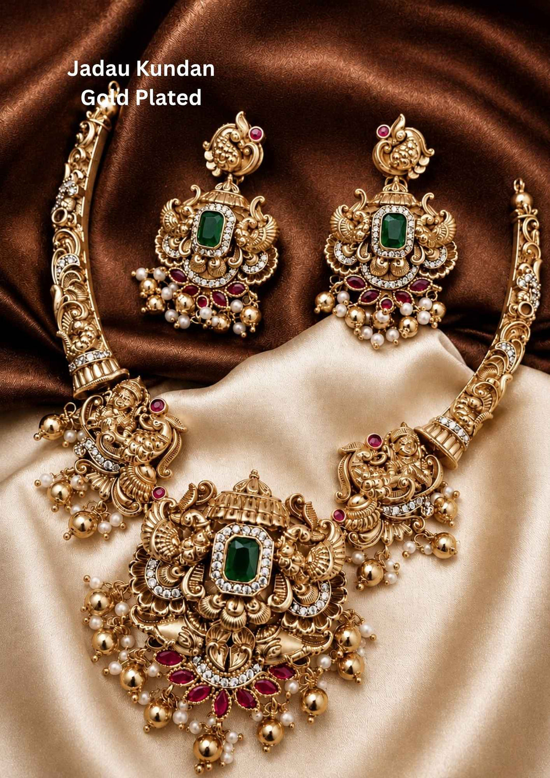 gold plated temple jewelry set featuring a structured, antique-finished collar choker necklace. The sides showcase carved figures of Goddess Lakshmi transitioning into a grand, ornate central pendant. The center pendant features a prominent rectangular emerald-green stone surrounded by white kundan crystals, peacock details, pink stone accents, and a fringe of dangling gold beads and white pearls.Perfect for festive celebrations with skin-friendly premium quality, comfortable wear,