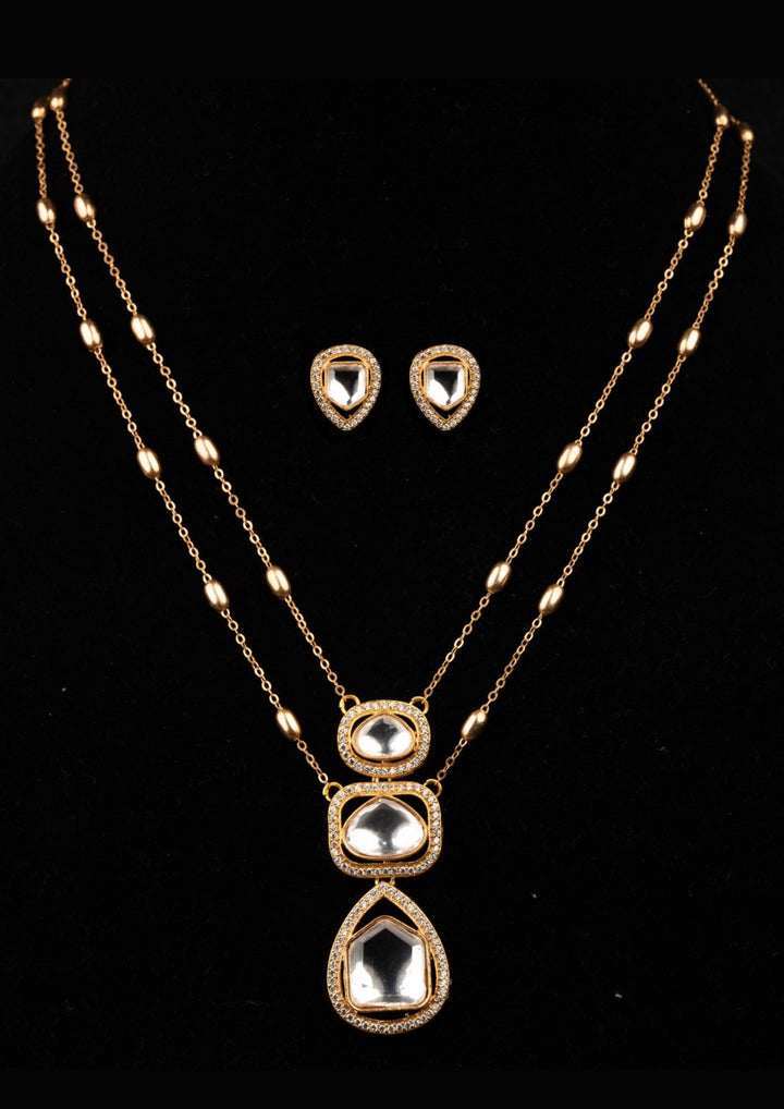 Gold necklace with pendant and matching earrings on a black background
