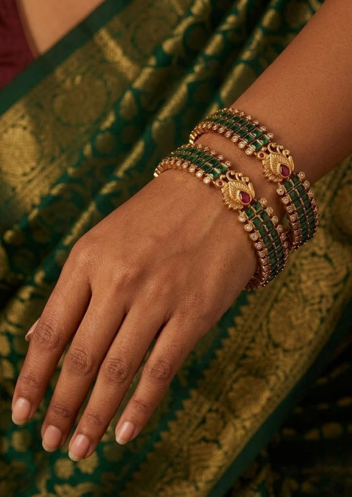 Close-up of a south indian woman wearing Gold Plated Kempu Bangles with traditional red and green kempu stone work that gives a grand bridal and festive jewelry look. The bangles show detailed temple-style pattern with lightweight design, sweat proof finish, anti-fade colour, smooth fitting, and are perfect for weddings, festivals, receptions, and cultural celebrations.