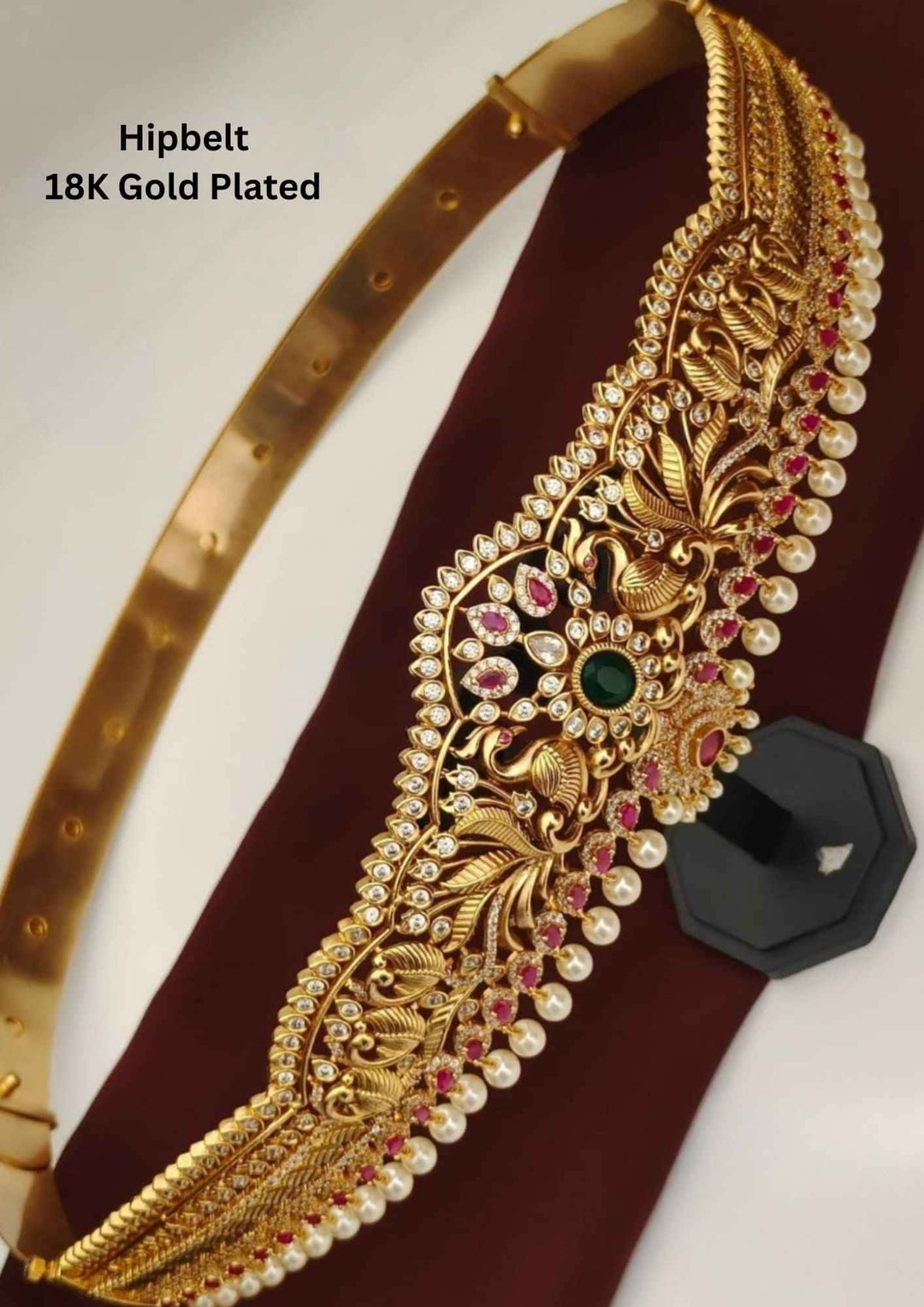 Gold-plated hip belt with intricate designs and gemstones on a white background