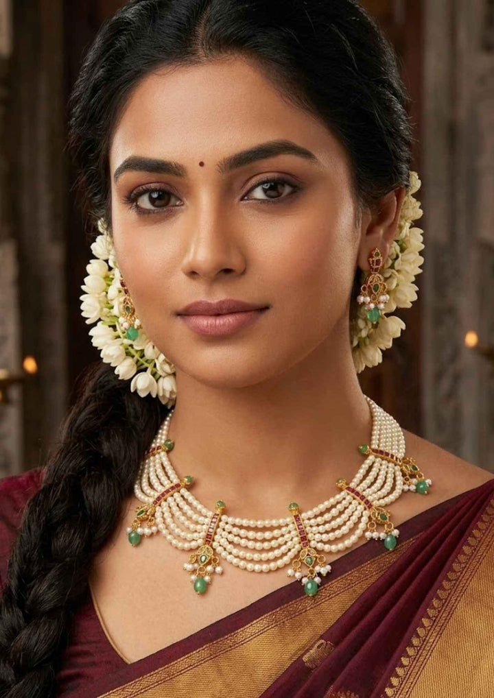 South indian Woman wearing Presentation of a Jadau Kundan gold plated multi-strand pearl festoon choker showing red ruby accents and dangling green teardrop emerald beads that give a graceful traditional and modern look for brides and grand poojas with COD.