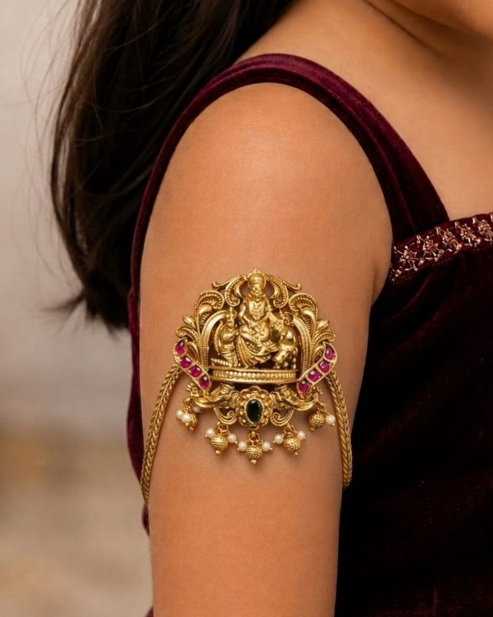Beautiful gold plated kids vanki featuring an ornate Goddess Lakshmi design with vibrant ruby and green stone detailing, intricate traditional craftsmanship, and pearl embellishments. Perfect for traditional wear, festivals, weddings, classical dance, and special occasions.