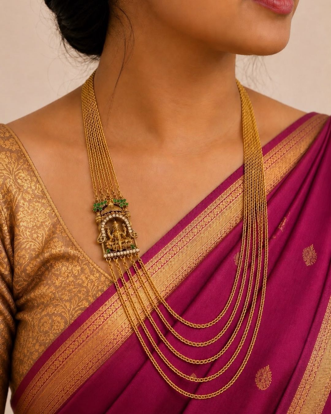 Gold-plated pendant necklace with a decorative floral design and small clear stones, displayed on a dark burgundy background with a gold satin fabric accent. Text overlay reads &