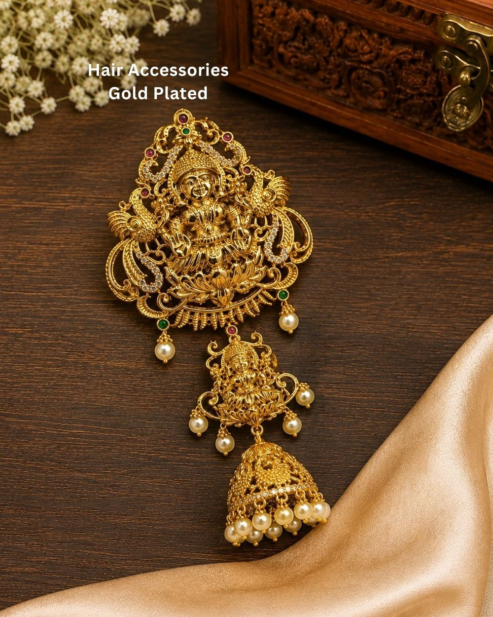 Beautiful traditional Lakshmi gold plated hair accessory featuring an intricate Goddess Lakshmi design, red and green stone accents, and multiple pearl drops. Perfect for festive occasions, traditional hairstyles, weddings, temple visits, and premium gifting.
