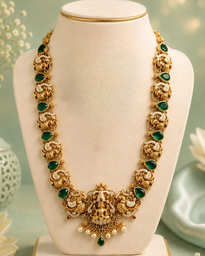 Premium antique gold plated temple necklace and earrings set crafted with intricate Ganesha and peacock designs, sparkling CZ stones, green accents, and elegant pearl details.