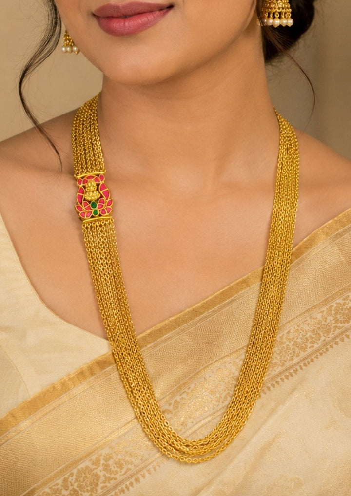 South Indian style multi strand gold plated necklace featuring a Lakshmi-inspired centerpiece and fine chain detailing. The long layered silhouette complements sarees, salwar suits and traditional outfits for festive occasions.