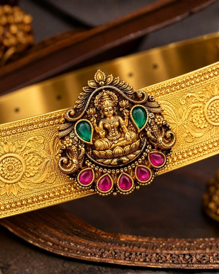 Beautiful gold plated kid’s hip belt featuring a wide engraved band with a traditional Lakshmi centerpiece decorated with ruby and green stones. Perfect for traditional wear, weddings, festive occasions, cultural events, parties, and gifting.