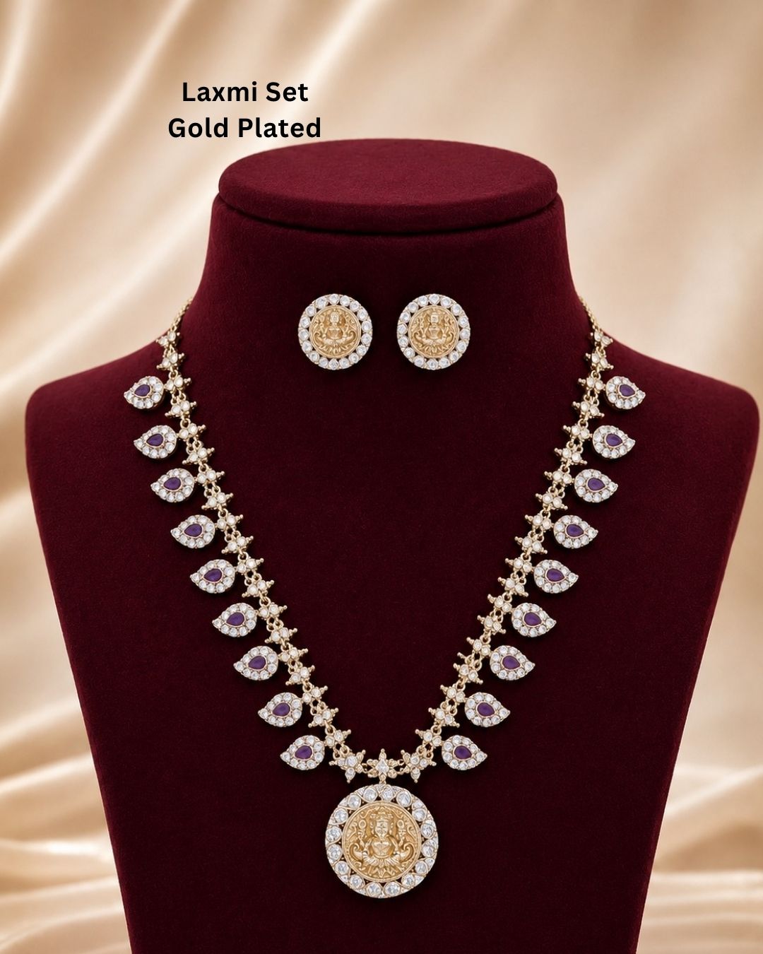 Elegant gold plated Lakshmi necklace set featuring ruby teardrop stones, sparkling zircon detailing, and a beautifully crafted Goddess Lakshmi pendant with matching designer stud earrings. Perfect for festive and bridal wear.