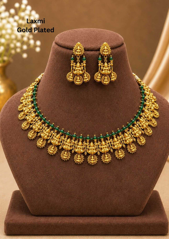 Traditional style gold plated temple long haram necklace designed with structured Nakshi panels of Goddess Laxmi, green bead accents, and an elegant matte gold finish that gives a graceful traditional look for festive celebrations, poojas, family functions, and bridal outfits.
