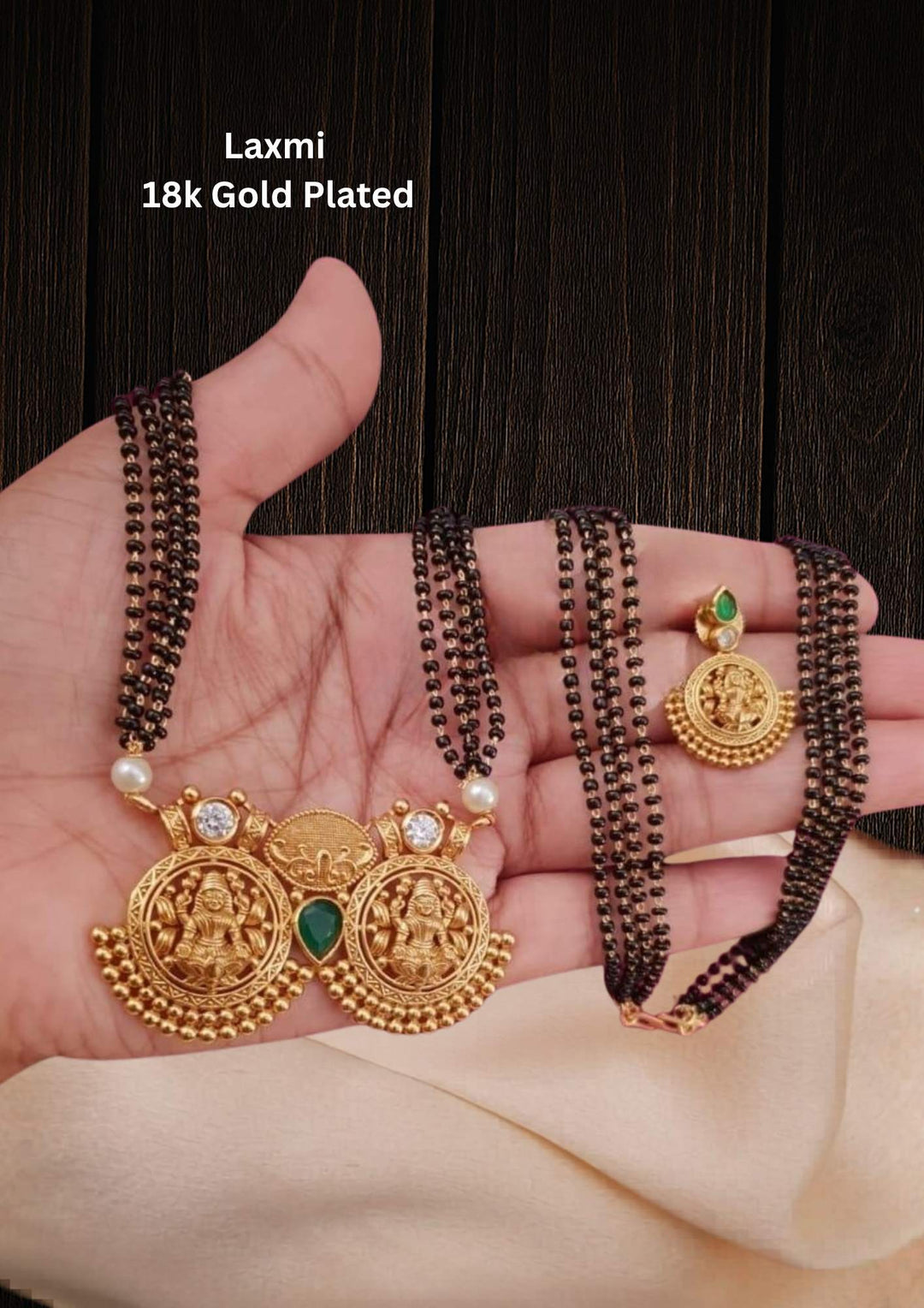 Gold Plated Laxmi Mangalsutra Set designed with Goddess Lakshmi pendant, traditional black bead chain, kundan used green emrald and white pearls it is lightweight perefect for daily wear, sweat proof coating, anti-fade polish, and skin-friendly material suitable for married women, pooja functions, festivals.