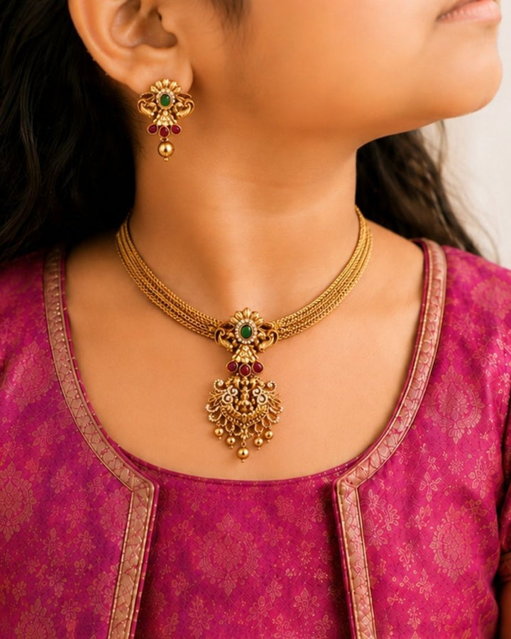 Gold-plated necklace and earrings set and in image clearly shown how it looks matching earrings, green stones, zircon detailing, and pearl drops. The temple jewelry design features Goddess Laxmi pendant with floral traditional patterns and antique gold finish. The layered necklace and matching earrings give a grand and elegant ethnic jewelry appearance. Comfortable, skin-friendly, sweat proof, and perfect for weddings, festivals, sarees, and family functions.