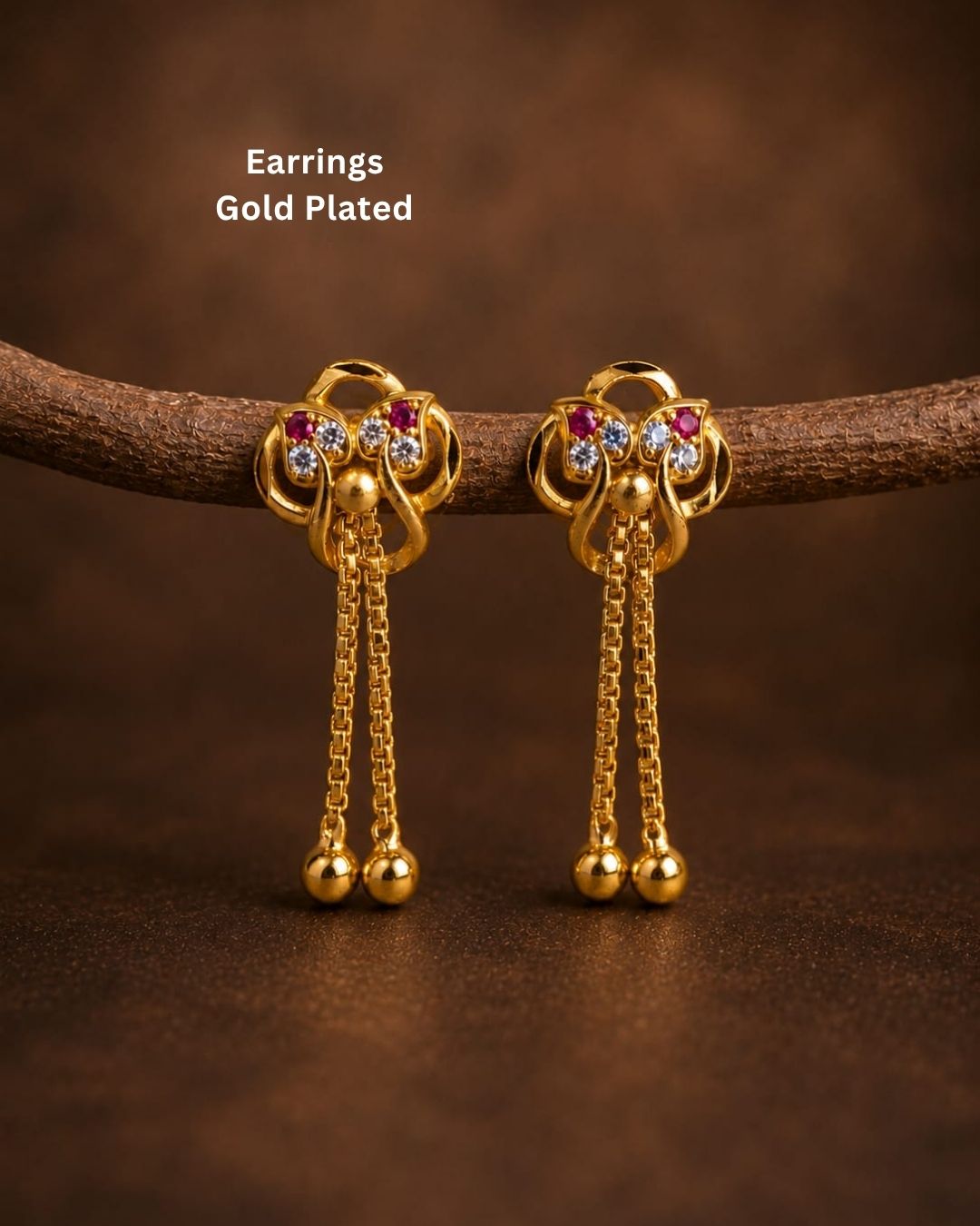 Shop Gold Plated Designer Long Drop Earrings featuring ruby and white stone detailing, intricate gold motifs, elegant chain drops, and polished gold ball accents. Perfect for festive and traditional occasions. COD available at Zevana.