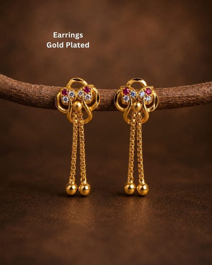 Shop Gold Plated Designer Long Drop Earrings featuring ruby and white stone detailing, intricate gold motifs, elegant chain drops, and polished gold ball accents. Perfect for festive and traditional occasions. COD available at Zevana.