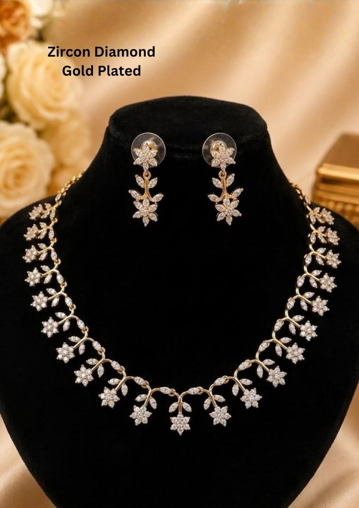 Gold-plated zircon diamond necklace and matching stud earrings. The necklace features a vine design with floral and leaf motifs set with clear stones. Beautiful zircon diamond gold plated floral necklace set featuring delicate flower and leaf motifs with matching earrings. Perfect for weddings, parties, festive occasions, and elegant daily styling.