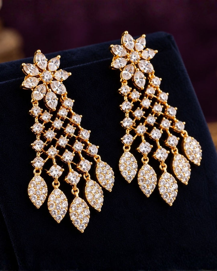 Modern Indian woman styling a zircon diamond gold plated necklace set with matching designer earrings. The jewelry features brilliant diamond-look zircon stones, delicate leaf-shaped danglers and a lightweight elegant finish that beautifully complements sarees, lehengas, gowns and traditional ethnic outfits.