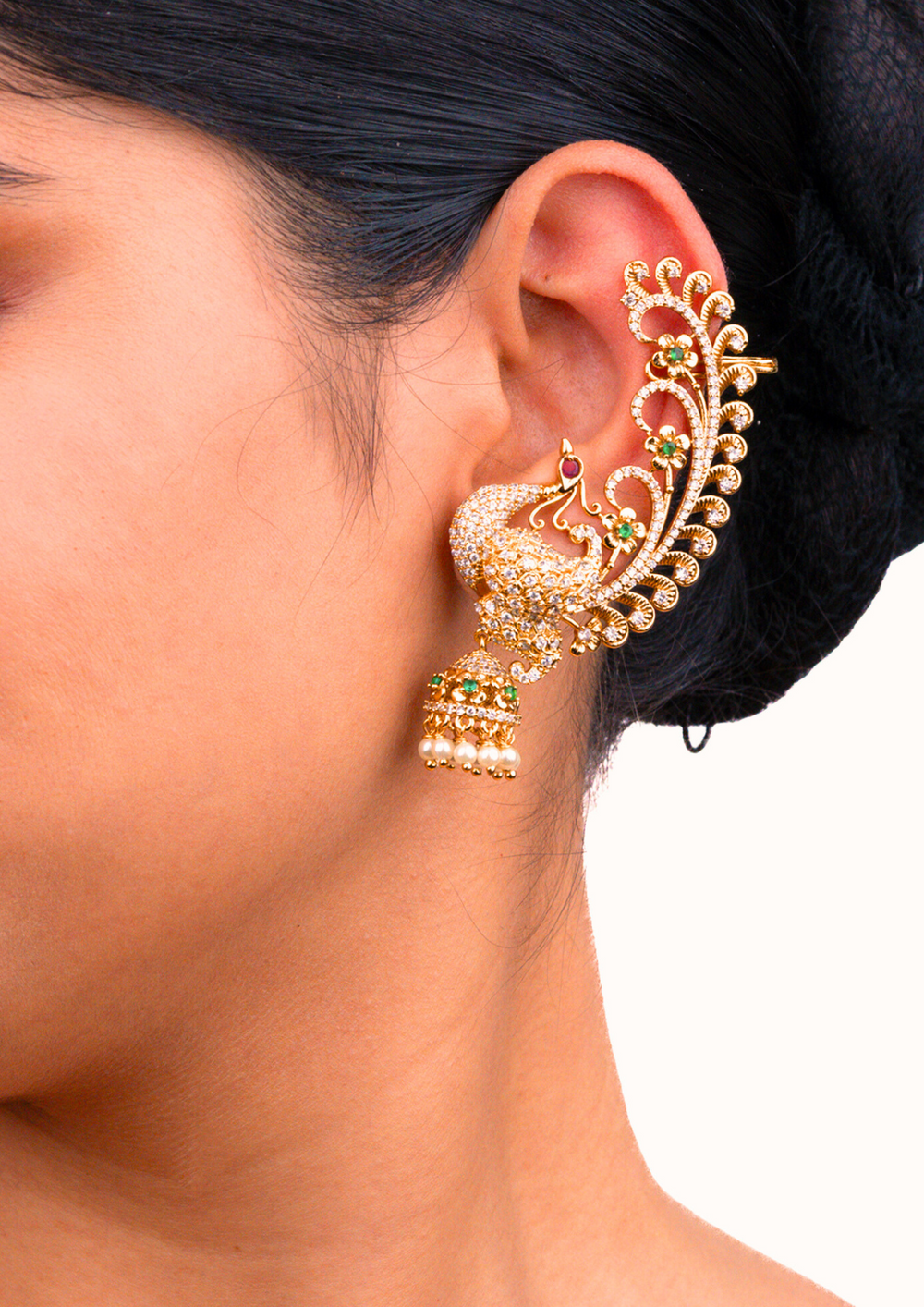 close up of south indian women wearing a Traditional style gold plated American diamond full ear cuffs designed with stone-studded peacock structures, red-green gemstone details, and hanging white jhumka pearls that give a graceful traditional look for festive celebrations, poojas, family functions, and bridal outfits with lightweight comfortable use.
