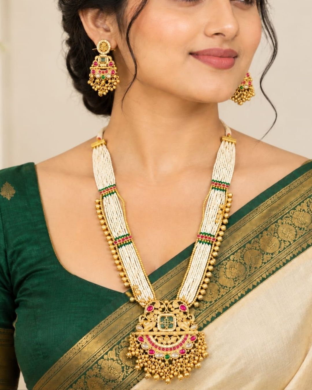 Traditional gold plated necklace set with layered white bead strands, green and pink stone accents, an elaborate pendant with dangling beads, and matching earrings, perfect for festive and ethnic occasions.