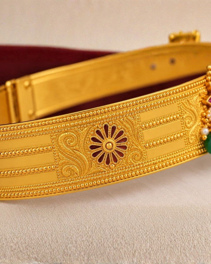 Beautiful gold plated kids hip belt featuring a wide intricately engraved band with traditional floral motifs and a decorative centerpiece adorned with vibrant green and pink stones, sparkling clear stones, and elegant green bead drops. Perfect for traditional wear, weddings, festivals, classical dance, special occasions, and gifting.