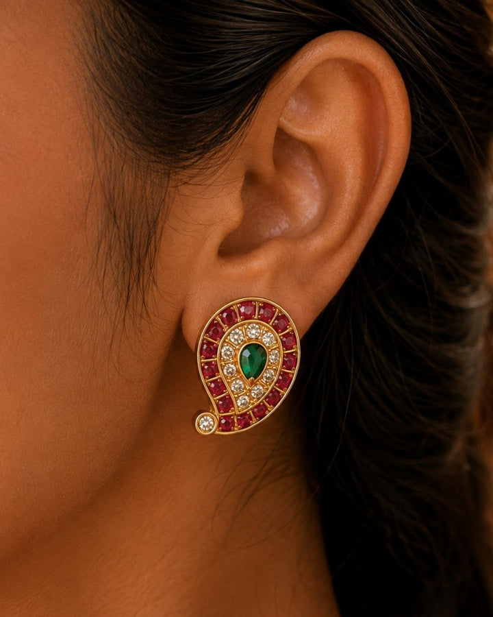 Beautiful Jadau Kundan gold plated pendant necklace set featuring a paisley motif with ruby red stones, a green center stone, sparkling kundan work, and matching earrings. Perfect for weddings, festivals, temple visits, traditional outfits, family functions, and premium gifting.